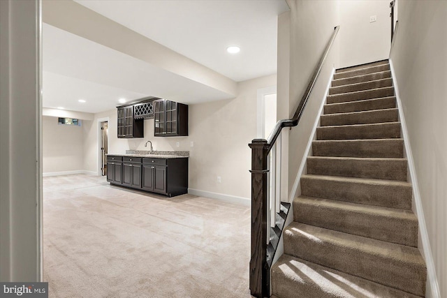 staircase with indoor wet bar and carpet floors