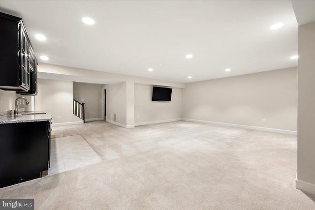 basement featuring light colored carpet and sink