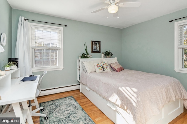 bedroom featuring multiple windows, ceiling fan, a baseboard radiator, and light wood-type flooring