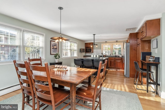 dining space with a healthy amount of sunlight, sink, and light hardwood / wood-style flooring