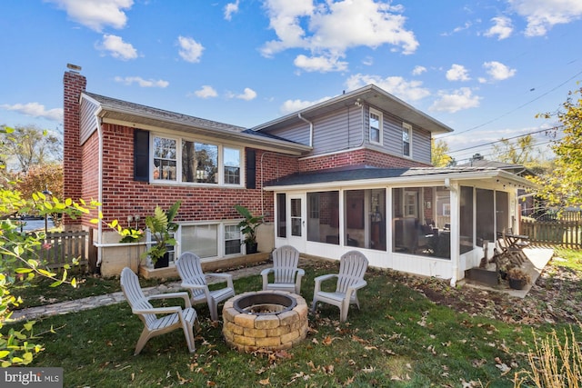 back of property with a sunroom and an outdoor fire pit