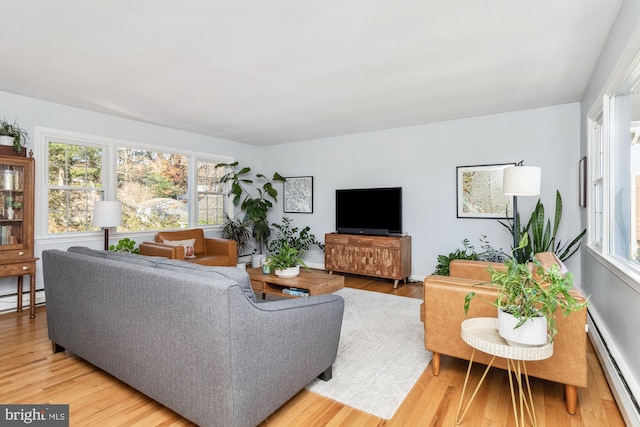 living room featuring hardwood / wood-style flooring, plenty of natural light, and a baseboard heating unit