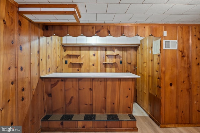 bar featuring light hardwood / wood-style flooring and wood walls