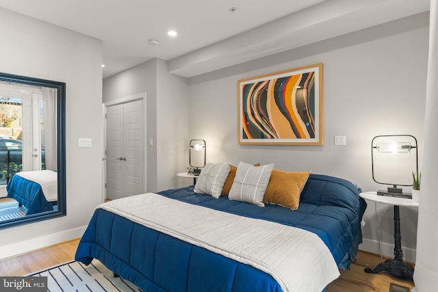 bedroom with access to exterior, light wood-type flooring, and a closet