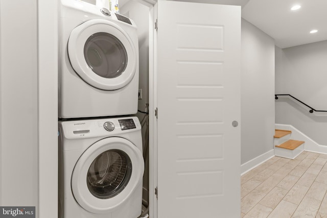 laundry area with stacked washer and dryer and light hardwood / wood-style flooring