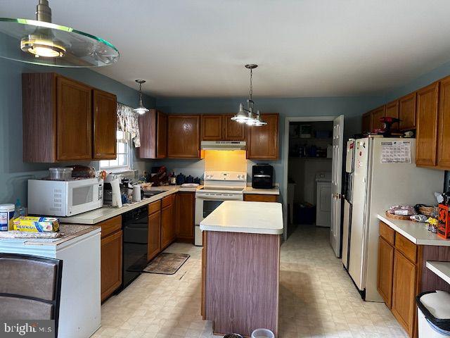 kitchen with a kitchen island, washer / dryer, white appliances, and hanging light fixtures