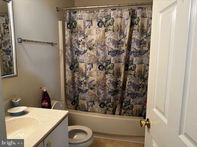 full bathroom featuring tile patterned floors, shower / tub combo with curtain, vanity, and toilet