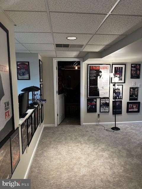 hallway featuring a paneled ceiling and carpet