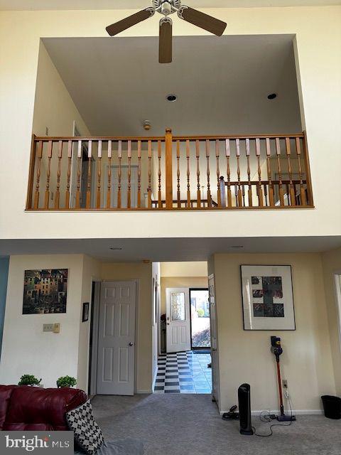 stairs featuring carpet, ceiling fan, and a towering ceiling