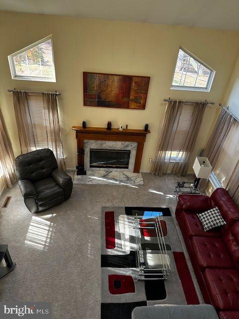 carpeted living room with plenty of natural light, a premium fireplace, and a towering ceiling