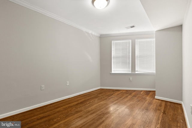 spare room featuring wood-type flooring and crown molding