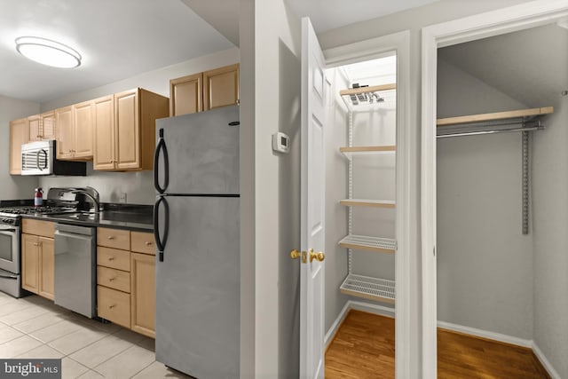 kitchen featuring light brown cabinetry, light wood-type flooring, and appliances with stainless steel finishes