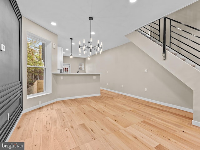 interior space with white cabinets, decorative light fixtures, light hardwood / wood-style floors, and an inviting chandelier