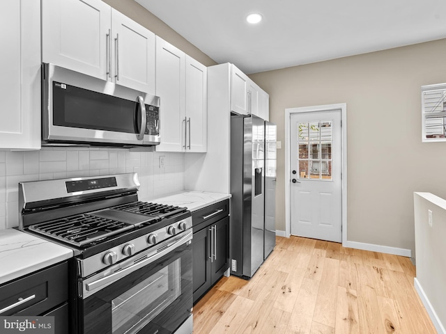 kitchen featuring tasteful backsplash, light stone counters, stainless steel appliances, light hardwood / wood-style flooring, and white cabinets