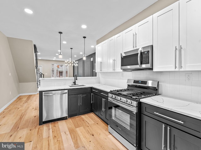 kitchen with sink, light hardwood / wood-style flooring, kitchen peninsula, white cabinets, and appliances with stainless steel finishes