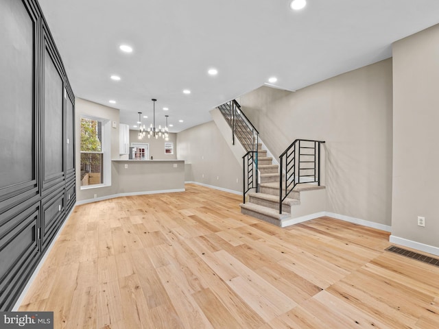 unfurnished living room featuring light hardwood / wood-style floors and a notable chandelier