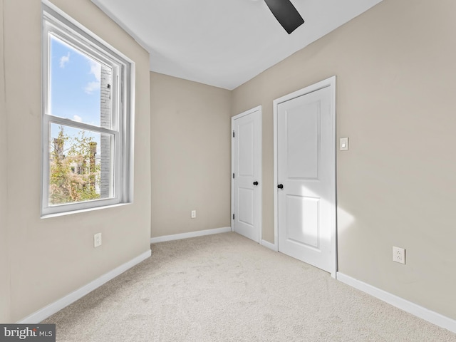 unfurnished bedroom featuring multiple windows, ceiling fan, and light colored carpet