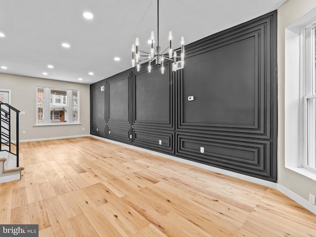 unfurnished dining area with a notable chandelier and light hardwood / wood-style floors