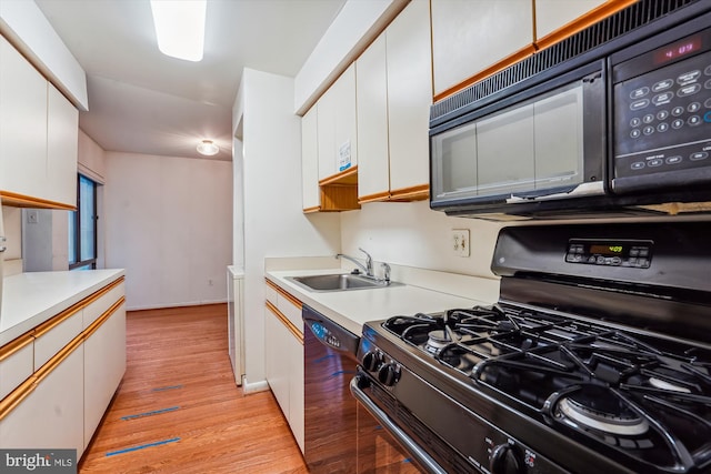 kitchen with white cabinetry, sink, light hardwood / wood-style flooring, and black appliances