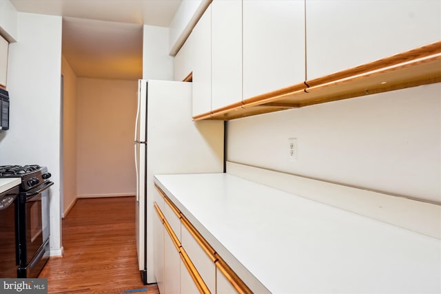 kitchen with white cabinets, light hardwood / wood-style floors, and black appliances