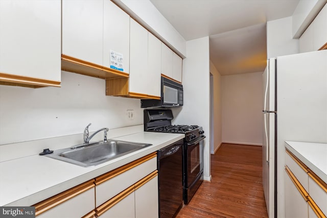 kitchen with white cabinetry, sink, black appliances, and hardwood / wood-style floors