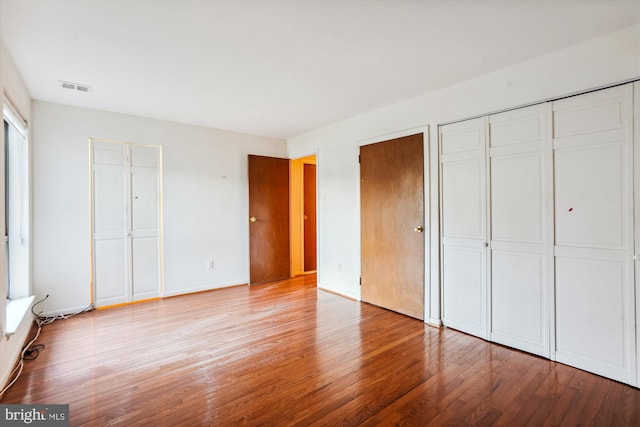 unfurnished bedroom with multiple closets and light hardwood / wood-style floors