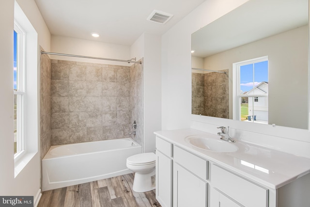 full bathroom with hardwood / wood-style flooring, vanity, toilet, and tiled shower / bath