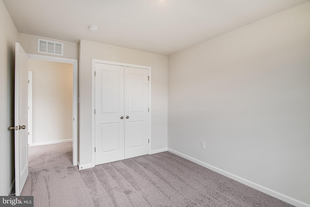 unfurnished bedroom with light carpet and a closet