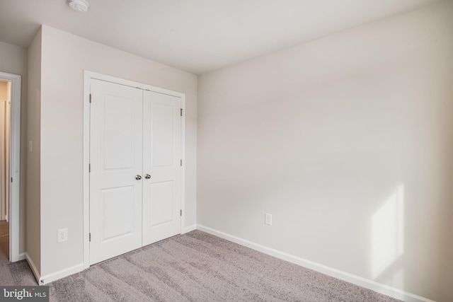 unfurnished bedroom featuring light colored carpet and a closet