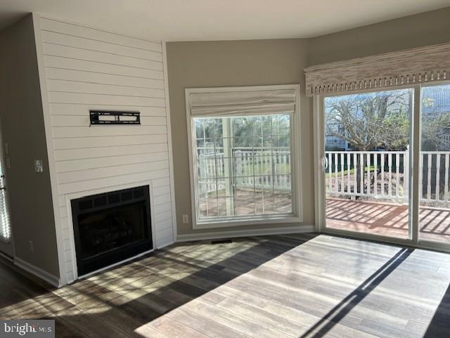 unfurnished living room with dark hardwood / wood-style flooring and a healthy amount of sunlight