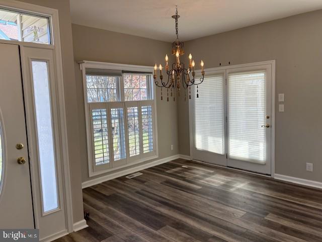 unfurnished dining area featuring a chandelier and dark wood-type flooring