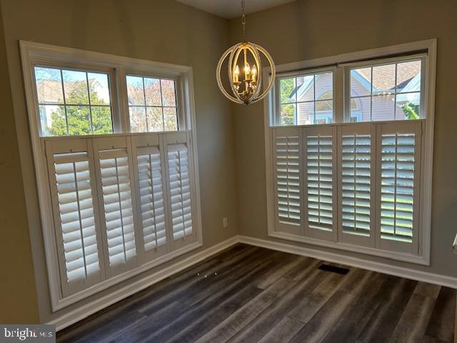 unfurnished dining area featuring dark hardwood / wood-style flooring and an inviting chandelier