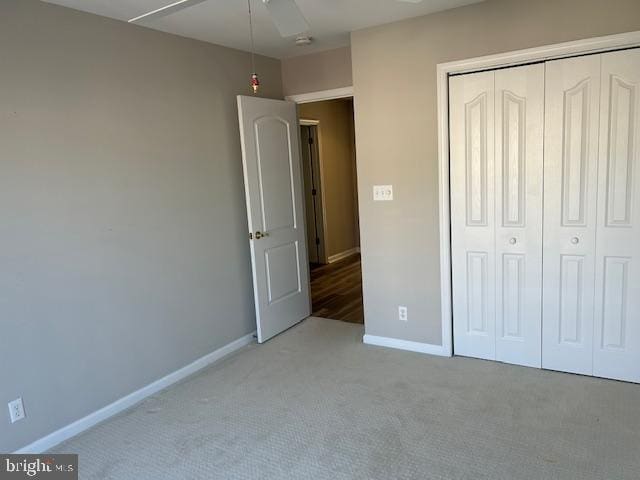 unfurnished bedroom with ceiling fan, light carpet, and a closet