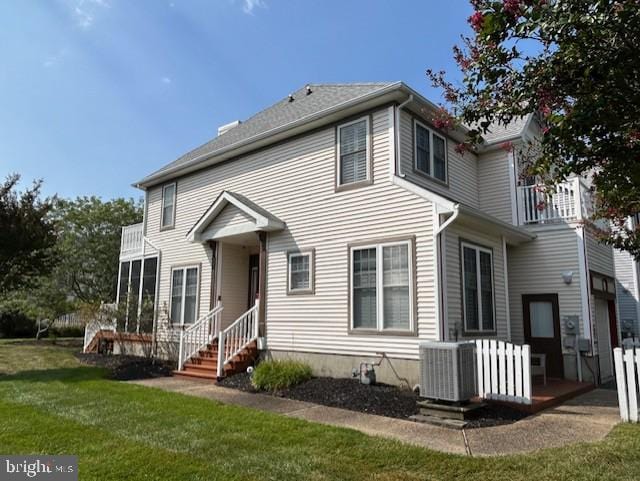 view of front of house featuring a front yard, a balcony, and cooling unit