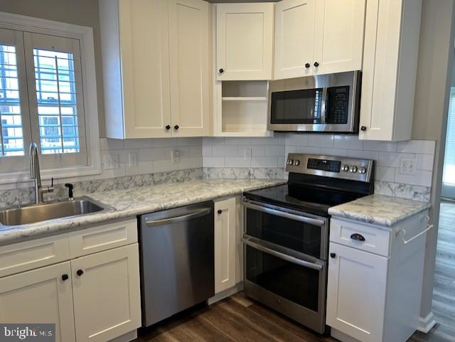 kitchen featuring white cabinets, appliances with stainless steel finishes, dark wood-type flooring, and sink