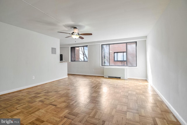 unfurnished living room with ceiling fan, radiator, and light parquet floors