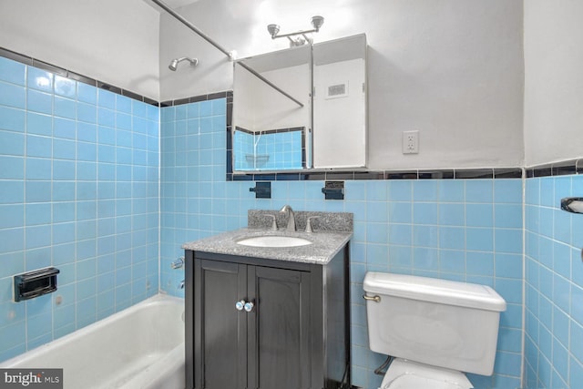 full bathroom featuring vanity, toilet, tile walls, and tiled shower / bath