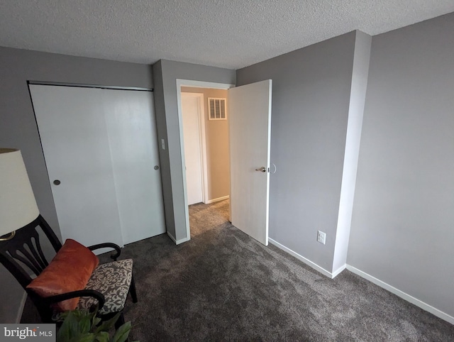 unfurnished bedroom with dark carpet, a textured ceiling, and a closet