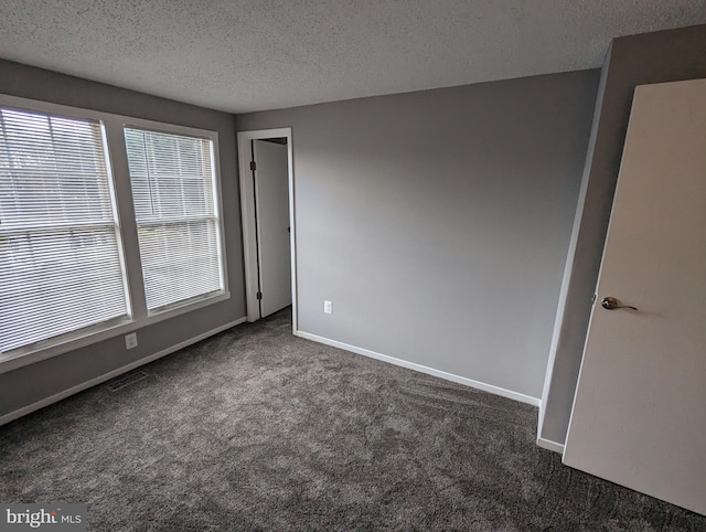 unfurnished room with dark colored carpet and a textured ceiling