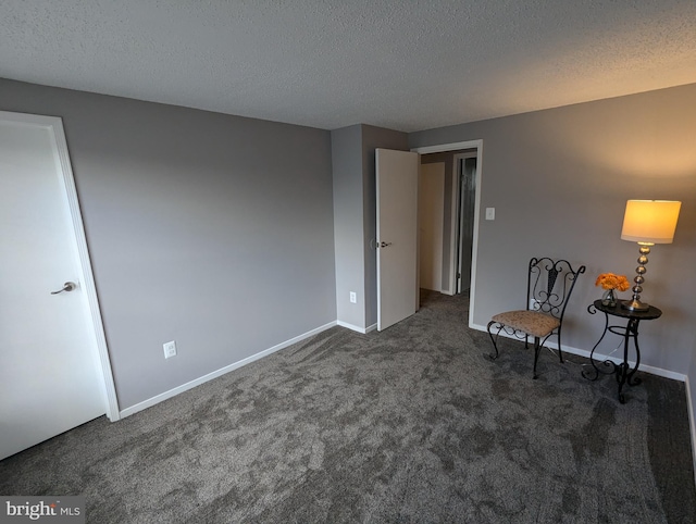 empty room with dark colored carpet and a textured ceiling