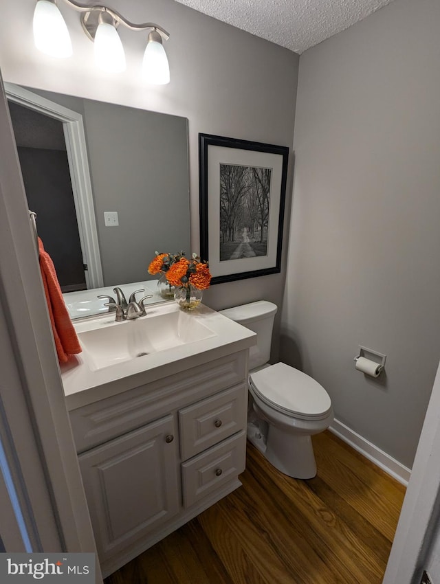 bathroom featuring vanity, hardwood / wood-style floors, a textured ceiling, and toilet