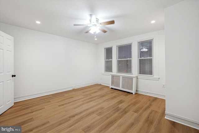 unfurnished room with ceiling fan, radiator heating unit, and light hardwood / wood-style floors