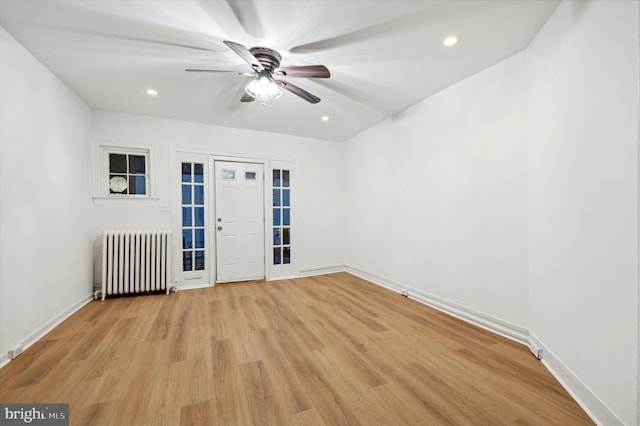 spare room with radiator heating unit, light wood-type flooring, and ceiling fan