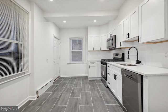 kitchen featuring white cabinetry, sink, appliances with stainless steel finishes, and a baseboard radiator