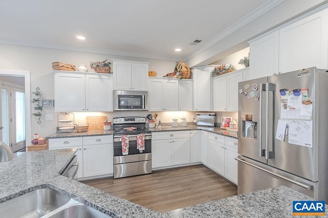 kitchen featuring white cabinets, crown molding, light stone countertops, dark hardwood / wood-style flooring, and stainless steel appliances