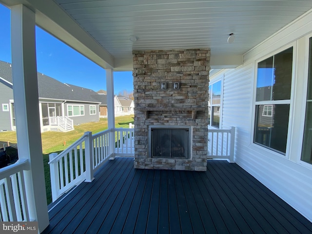 wooden terrace featuring a lawn and an outdoor stone fireplace