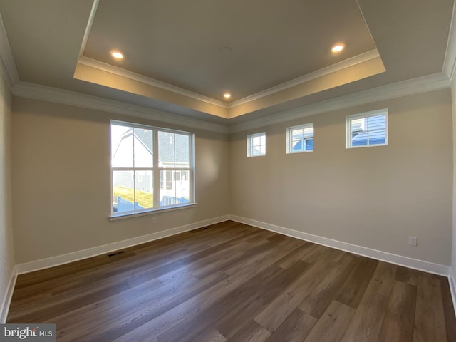 unfurnished room with a tray ceiling, crown molding, and dark hardwood / wood-style flooring