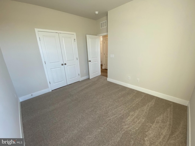 unfurnished bedroom featuring a closet and dark colored carpet