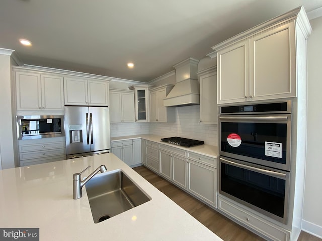 kitchen featuring sink, dark wood-type flooring, stainless steel appliances, backsplash, and custom range hood