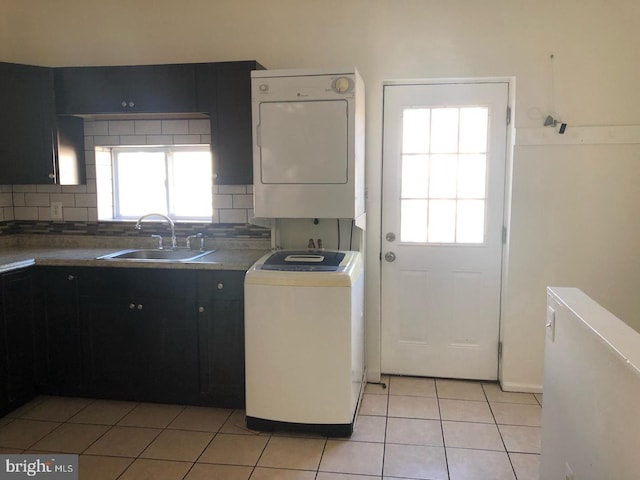 kitchen with tasteful backsplash, sink, light tile patterned flooring, and stacked washer and clothes dryer